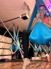 a woman sitting in a hammock in a yoga studio